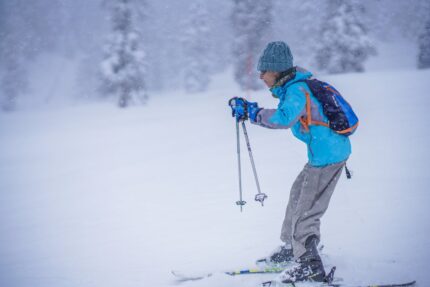 Man in Blue Jacket and Brown Pants Standing on Snow Covered Ground